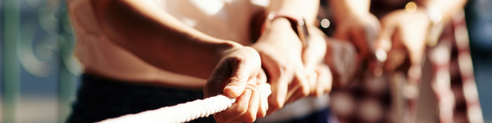 Cropped image of coworkers playing tug of war for developing cooperation and support in business team